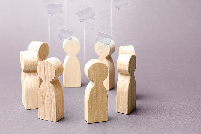 Inviting Questions to Spark Better Conversations; Wooden figures in conversation bubbles.