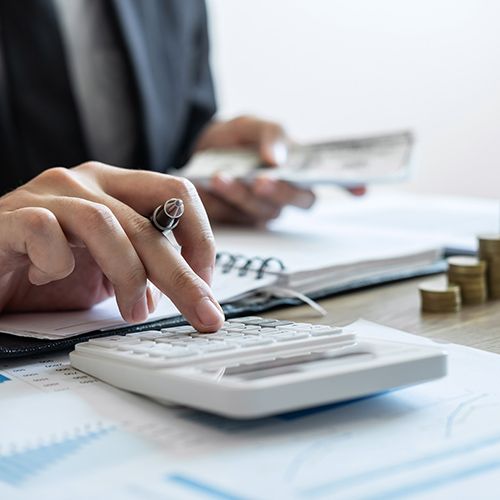 Person holding cash and using calculator