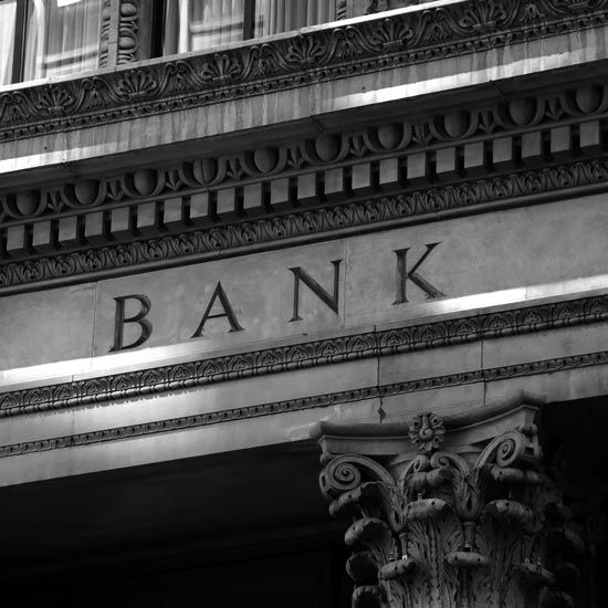 Fraud-Watch-FEATURE - Old style bank stonework sign with Corinthian column and design work.
